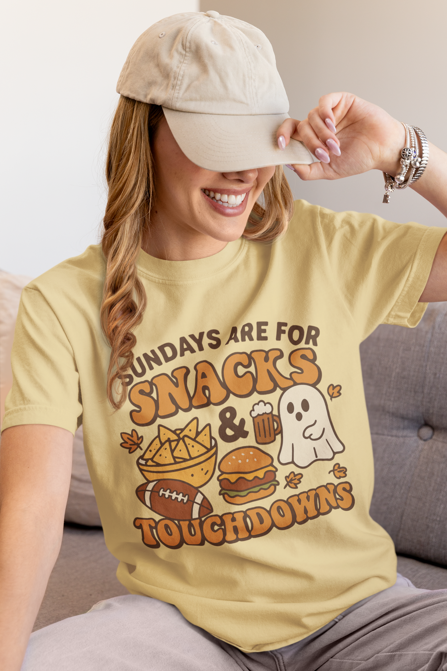 Woman wearing a yellow t-shirt with a graphic design and text, sitting on a couch.