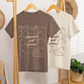 Two t-shirts with autumn-themed designs hanging on a wooden rack.