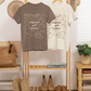 Two t-shirts on a rack with boots and decor items in a room.