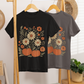Black and gray t-shirts with floral and pumpkin design hanging on a wooden rack.