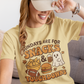 Woman wearing a yellow t-shirt with a graphic design and text, sitting on a couch.