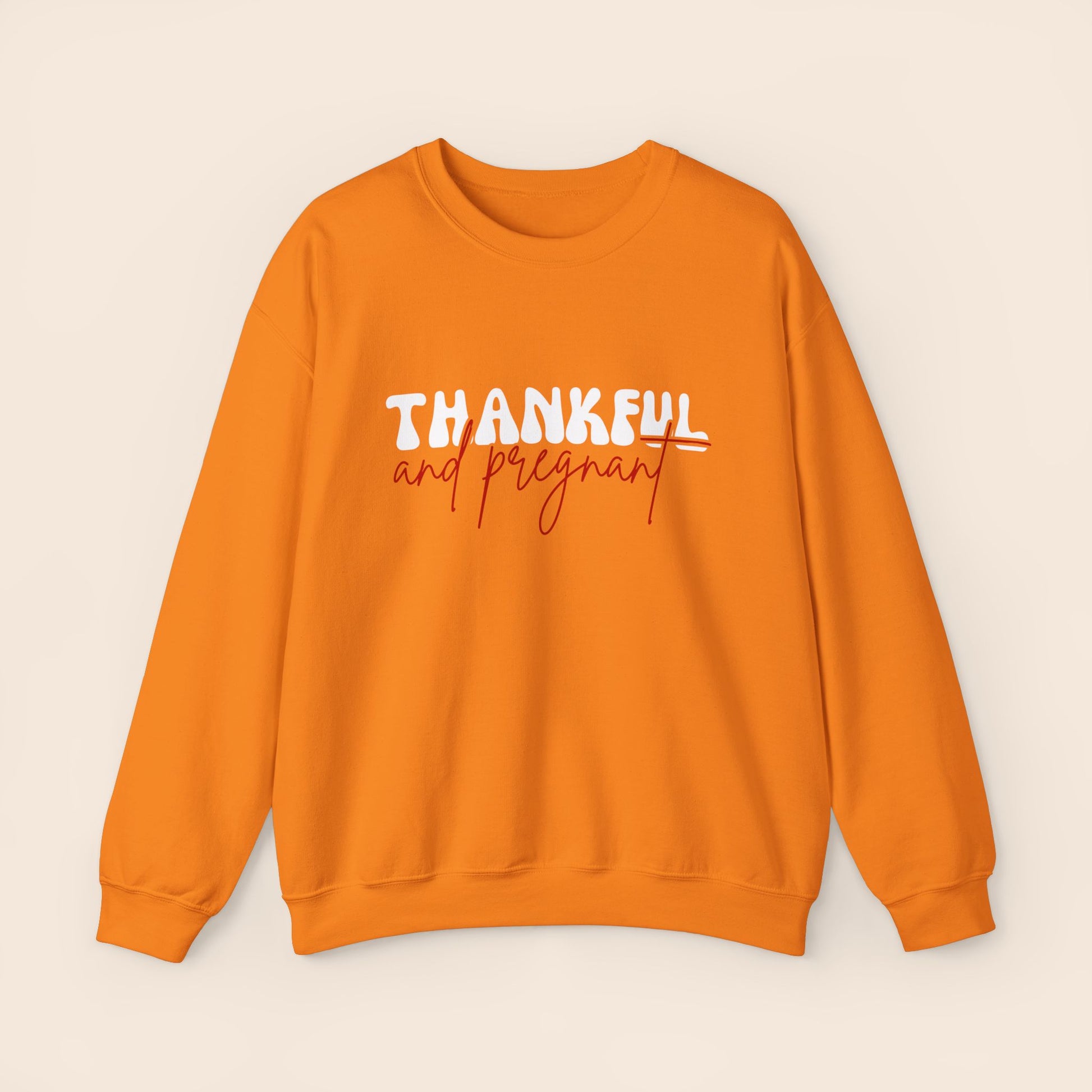 An orange crewneck sweatshirt with the text 'THANKFUL AND PREGNANT' printed.